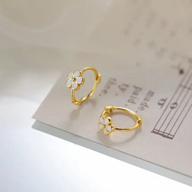 Gold hoop earrings with floral designs on a music sheet background